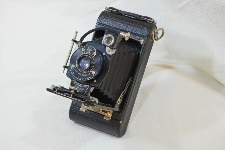 an old camera sitting on top of a white sheet, a portrait, inspired by August Sander, unsplash, bauhaus, folded, android cameraphone, full front view, australian