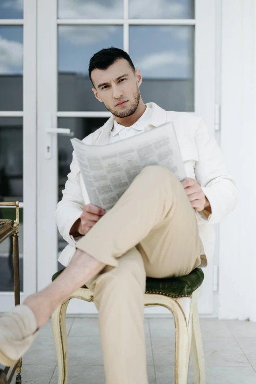 a man sitting on a chair reading a newspaper, inspired by Ramon Pichot, pexels contest winner, white trendy clothes, tan suit, ukrainian, young handsome pale roma