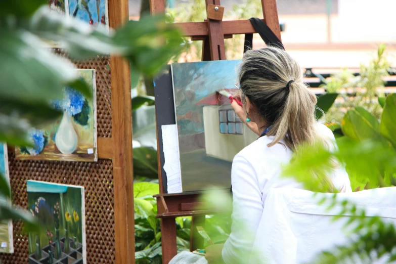 a woman standing in front of a painting on a easel, pexels contest winner, academic art, al fresco, profile image, gardening, subject in the centre