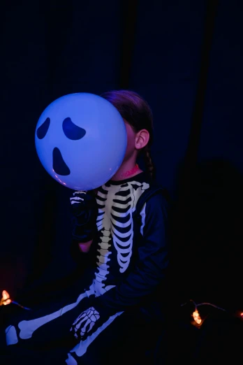a person holding a balloon with a skeleton on it, inspired by Gottfried Helnwein, pexels contest winner, glowing blue face, little kid, closed mouth showing no teeth, concert