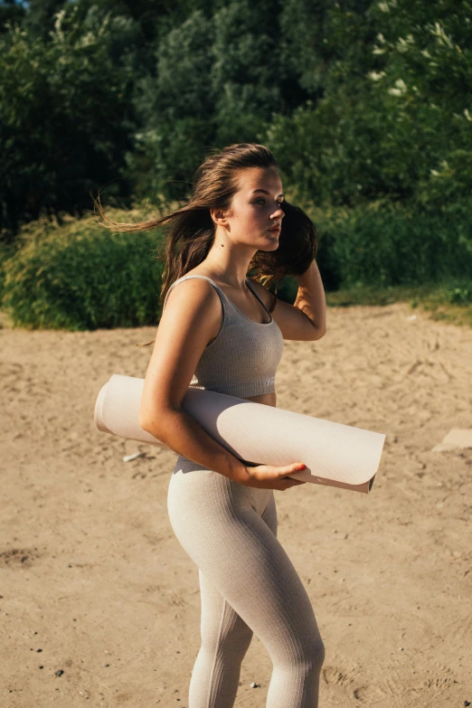a woman standing on top of a sandy beach, working out in the field, neoprene, light tan, trending photo