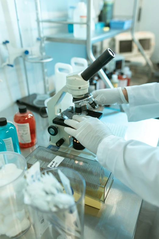 a person in a lab coat using a microscope, gloves on hands, #trending, thumbnail, medical supplies