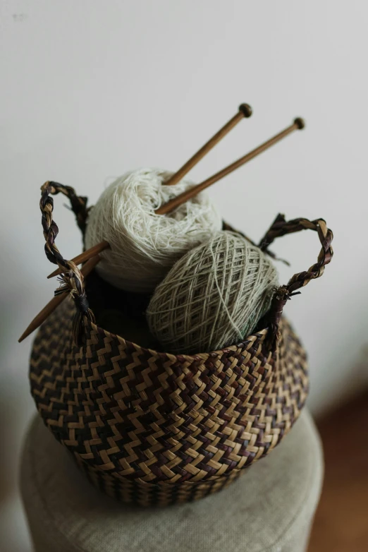 a close up of a basket with yarn and knitting needles, a digital rendering, unsplash, arts and crafts movement, bali, indoor setting, brown, grey