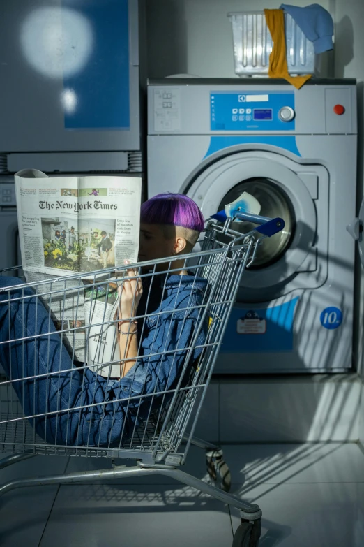 a man sitting in a shopping cart in front of a washing machine, by Matthias Stom, pexels contest winner, private press, reading a newspaper, 15081959 21121991 01012000 4k, colored photo, spy