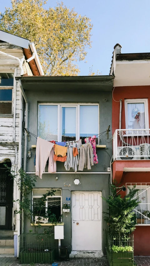 a couple of houses that are next to each other, a colorized photo, pexels contest winner, modernism, laundry hanging, istanbul, flat grey color, front