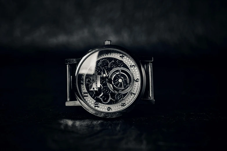 a close up of a watch on a table, a black and white photo, by Adam Marczyński, pexels contest winner, surrealism, titanium skeleton, thumbnail, low light, glossy intricate design