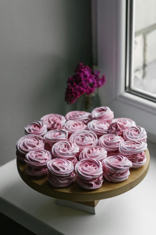 a cake sitting on top of a table next to a window, pink bees, spiral, ready to eat, piled around