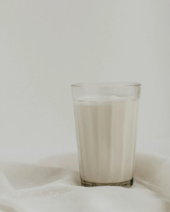 a glass of milk sitting on top of a bed, white clay, white backdrop, background image, white cloth