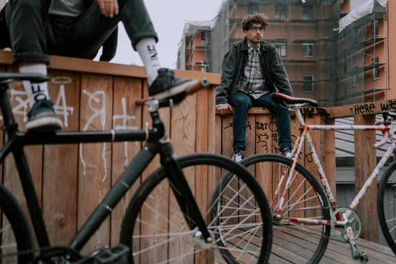 a man sitting on top of a wooden fence next to a bike, a portrait, pexels contest winner, two models in the frame, kacper niepokolczycki, college, transparent background