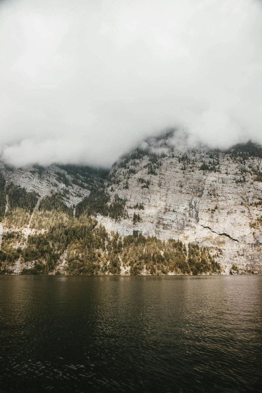 a large body of water with a mountain in the background, by Johannes Voss, unsplash contest winner, romanticism, steep cliffs, overcast lake, germany, slightly pixelated