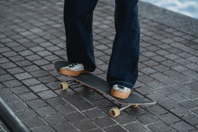 a person standing on a skateboard on a sidewalk, pexels contest winner, worn pants, corduroy, no watermarks, wearing jeans and a black hoodie