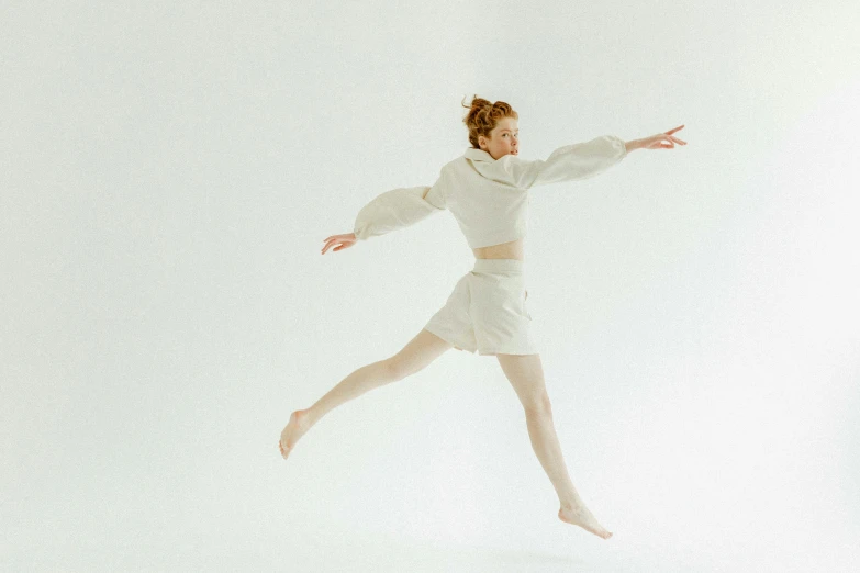 a woman that is jumping in the air, an album cover, inspired by Elizabeth Polunin, unsplash, arabesque, wearing a white sweater, ivory pale skin, white studio, sadie sink