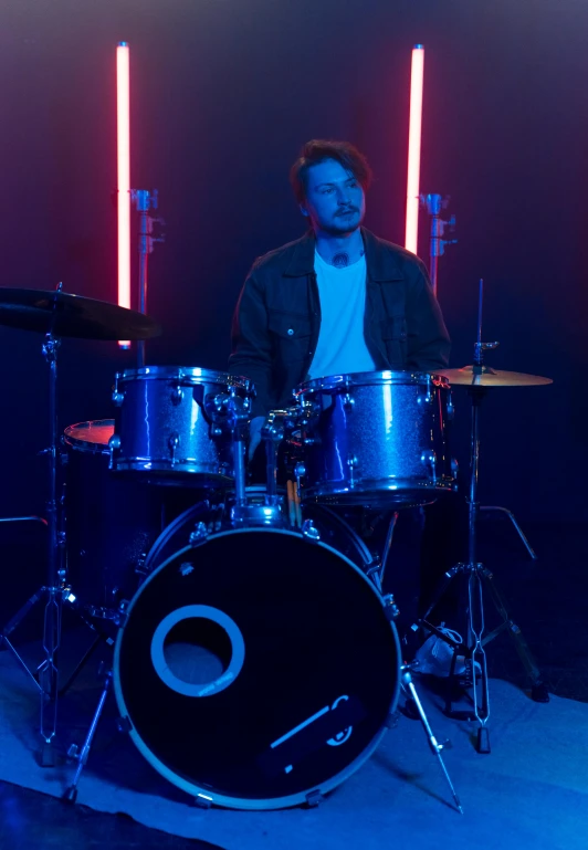 a man that is sitting in front of a drum set, profile image, blue lighting, charli bowater, avatar image