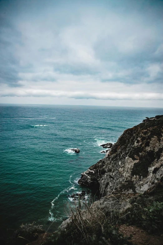 a view of the ocean from a cliff, a photo, by Kristin Nelson, pexels contest winner, overcast gray skies, teal color graded, pch, high quality photo