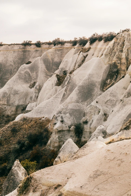 a person standing on the edge of a cliff, inspired by Elsa Bleda, trending on unsplash, surrealism, tall stone spires, turkey, 35 mm photo, panorama