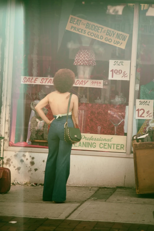 a woman standing in front of a store, inspired by Bruce Davidson, trending on pexels, happening, 7 0 s cinestill, with his back turned, with afro, vintage clothing