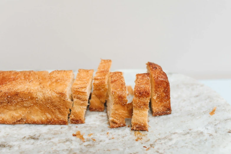 a piece of bread sitting on top of a white plate, a marble sculpture, by Carey Morris, unsplash, sliced bread in slots, very crispy, blond, on a pale background