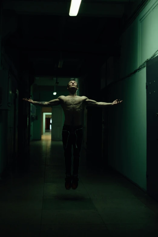 a man that is standing in the middle of a hallway, an album cover, inspired by Elsa Bleda, pexels contest winner, male calisthenics, his arms spread. ready to fly, steven klein, floating in air