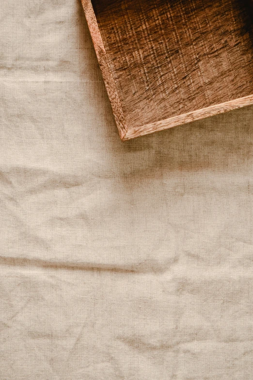 a wooden box sitting on top of a white sheet, inspired by Marià Fortuny, trending on unsplash, fabric texture, light brown, 1 5 9 5, tablecloth