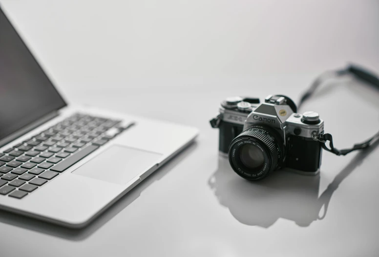 a camera and a laptop on a table, on a white table, today's featured photograph, photograph, close up photograph