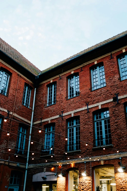 a couple of people that are standing in front of a building, by Jan Tengnagel, unsplash, renaissance, red bricks, string lights, barracks, lots de details