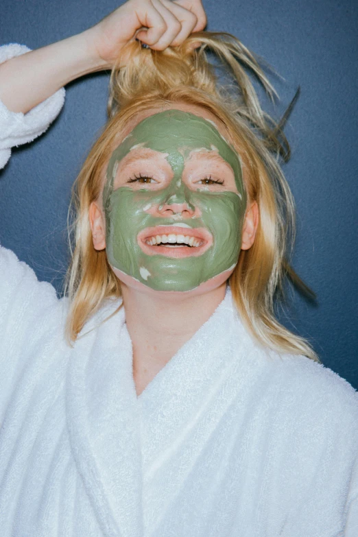 a woman with a green mask on her face, trending on pexels, a still of a happy, blond, lush, gooey skin