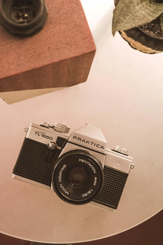 a camera sitting on top of a glass table, unsplash contest winner, photorealism, vintage soft grainy, flat lay, pentax k-1000, 1970's