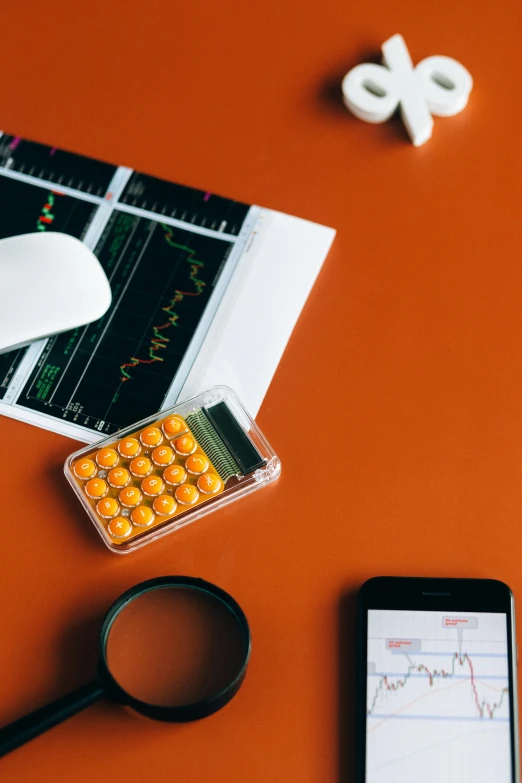 a cell phone sitting on top of a desk next to a magnifying glass, a picture, analytical art, orange color scheme, trading stocks, thumbnail, formulas