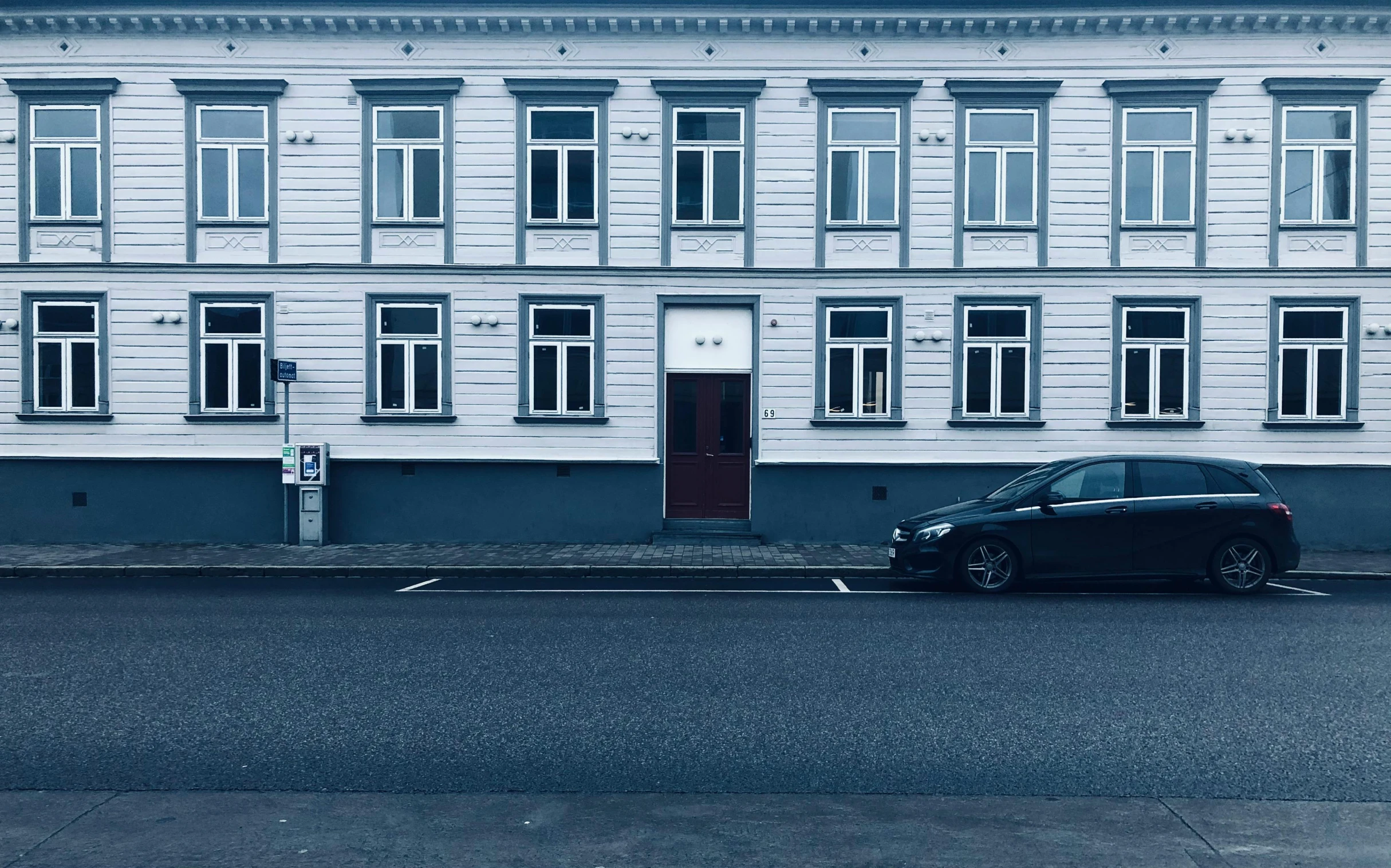 a black car parked in front of a white building, by Kristian Zahrtmann, pexels contest winner, prussian blue, hammershøi, street elevation, no - text no - logo