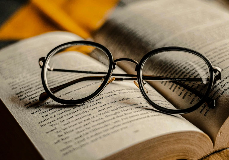 a pair of glasses sitting on top of an open book, story, square rimmed glasses, thumbnail, round black glasses