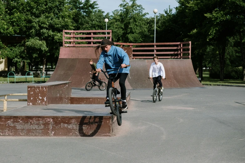 a man riding a bike up the side of a ramp, by Jaakko Mattila, pexels contest winner, park in background, kids playing, carving, low quality footage