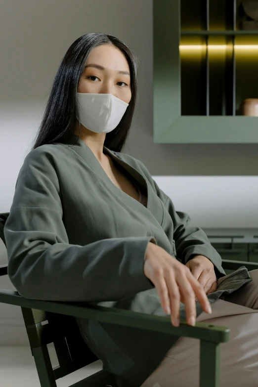 a woman sitting in a chair wearing a face mask, inspired by Fei Danxu, trending on pexels, renaissance, made of high tech materials, office clothes, mariko mori, smug look