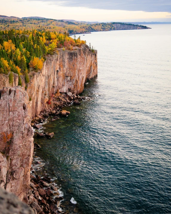 a cliff on the edge of a body of water, fall vibrancy, photo from above, superior look, owen klatte