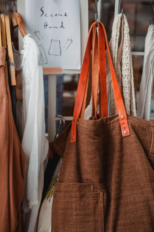 a couple of bags that are on a rack, by Jessie Algie, trending on pexels, renaissance, blacksmith apron, wearing a linen shirt, orange details, brown color palette