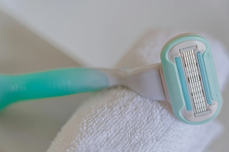 a close up of a razor on a towel, by Gina Pellón, pexels contest winner, happening, pastel colored, white and teal garment, shaved temple, teeth bared