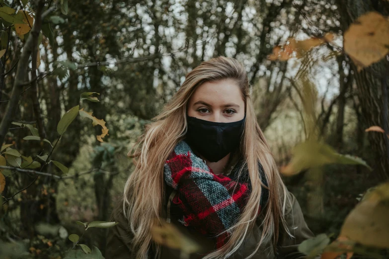 a woman wearing a face mask in the woods, by Emma Andijewska, trending on pexels, happening, black scarf, bushes in the background, young blonde woman, various posed