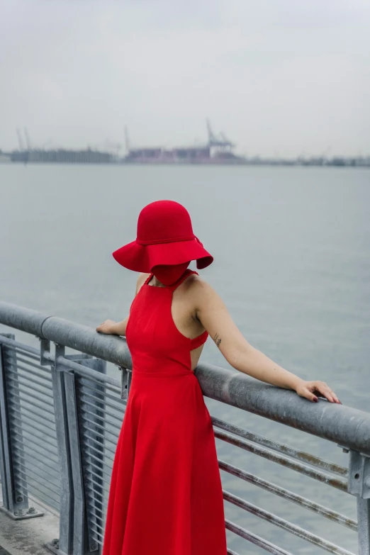 a woman in a red dress and a red hat, pexels contest winner, harbor, human staring blankly ahead, skyline, face obscured