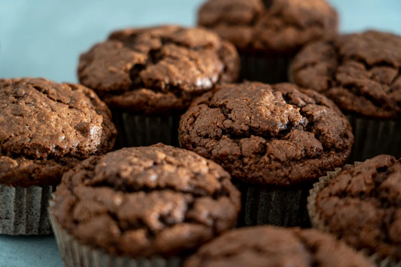 a pile of chocolate muffins sitting on top of a table, by Frederik Vermehren, unsplash, low - angle shot, 🦩🪐🐞👩🏻🦳, dynamic closeup, high resolution product photo