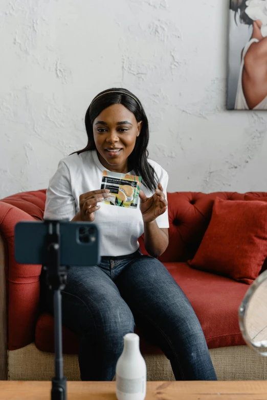 a woman sitting on a couch holding a credit card, a polaroid photo, happening, tiktok video, mkbhd, photoshoot for skincare brand, sitting in front of a microphone