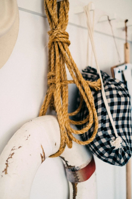 a hat and a life preserver hanging on a wall, inspired by Sarah Lucas, unsplash, hoog detail, ropes, pouches, indoor picture