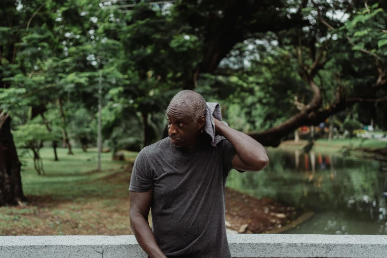 a man talking on a cell phone in a park, by Sam Charles, pexels contest winner, wet tshirt, man is with black skin, middle aged balding superhero, malaysian