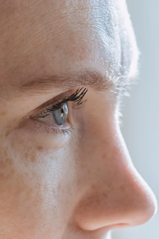 a close up of a person with a cell phone, eyelids, from the side, sparse freckles, light grey-blue eyes