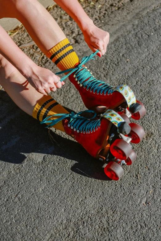 a woman riding a skateboard down a street, an album cover, by Jessie Algie, unsplash, red and teal and yellow, laces and ribbons, rollerskates, striped socks