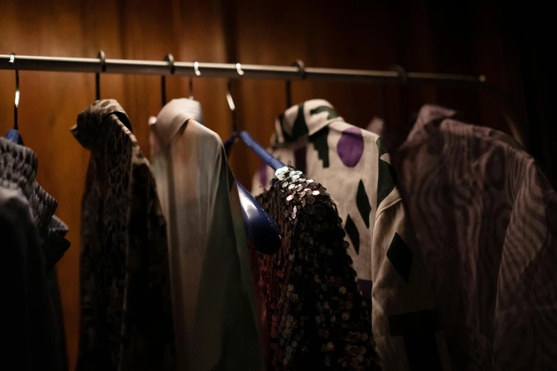 a bunch of clothes hanging on a rail, a portrait, unsplash, process art, fashion week backstage, patterned clothing, saggy purple robes, evening lighting