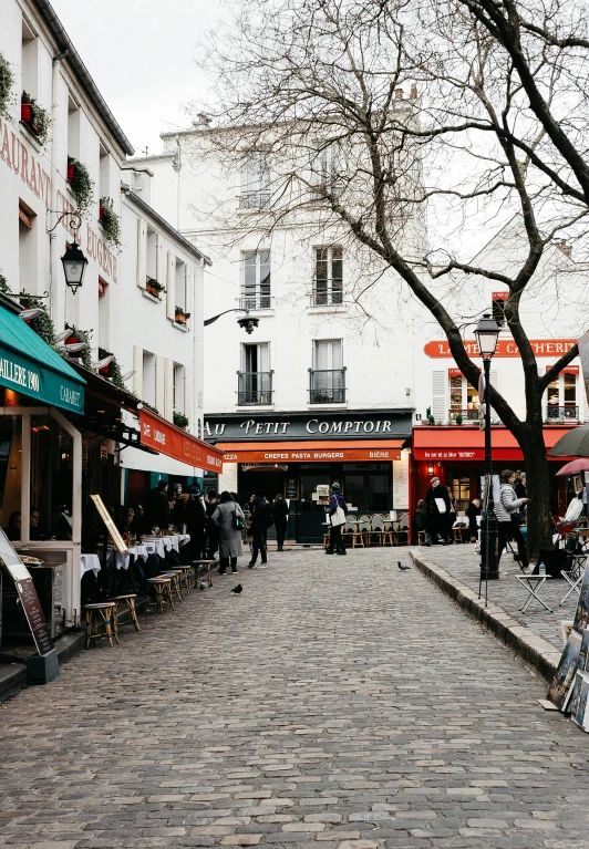 a woman holding an umbrella walks down a cobblestone street, by Julia Pishtar, trending on unsplash, paris school, cafe tables, square, carson ellis, medium