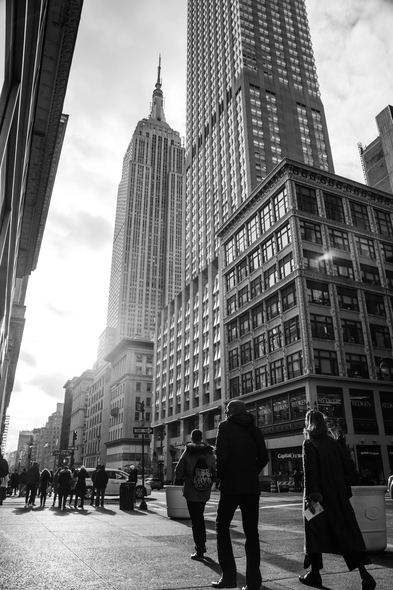 a group of people walking down a street next to tall buildings, a black and white photo, unsplash contest winner, empire state building, instagram picture, in 2 0 1 5, sunny day