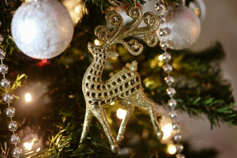 a close up of a christmas tree with ornaments, pexels, arabesque, deer, gold plated, organic ornament, long thick shiny gold beak