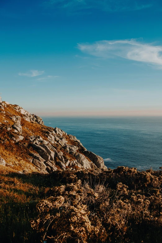 a man standing on top of a mountain next to the ocean, by Daniel Seghers, pexels contest winner, baroque, panoramic, portugal, slide show, rocky grass field