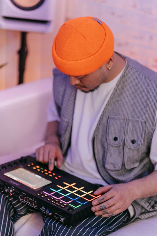 a man in an orange turban sitting on a couch, an album cover, trending on pexels, process art, dj mixer, drum pads, soft warm light, using synthesizer