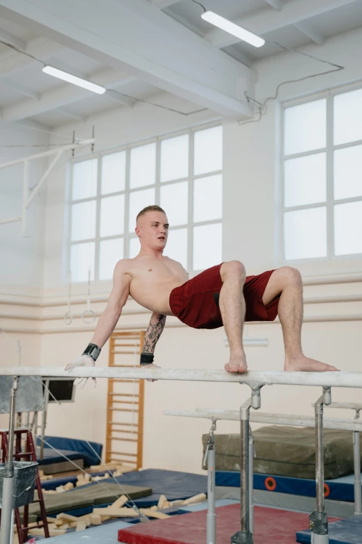 a man on a balance beam in a gym, a portrait, by Ilya Ostroukhov, pexels contest winner, modernism, train with maroon, buzzed hair on temple, gif, rubber undersuit